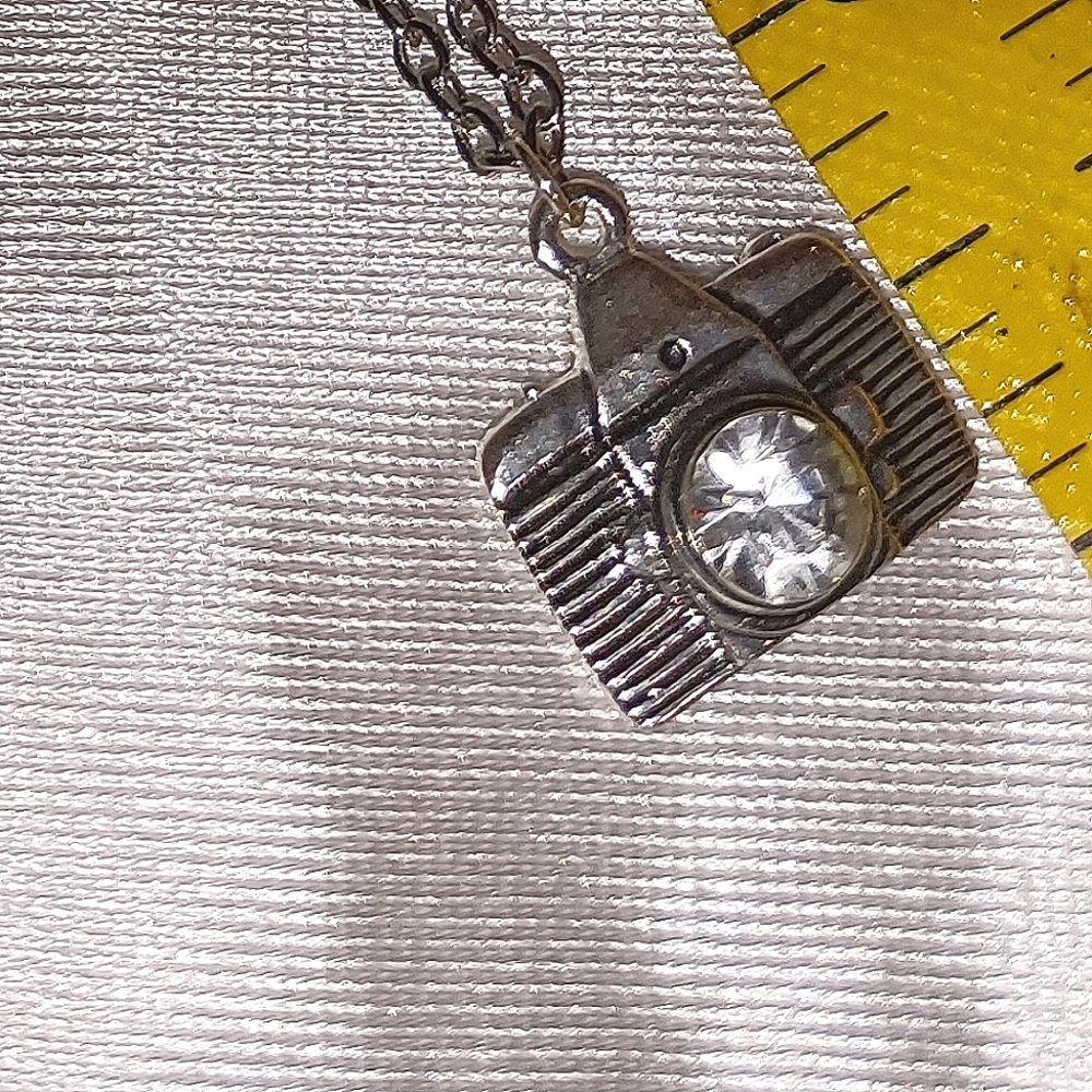 Photographers bling silver tone camera pendant with rhinestone lens.